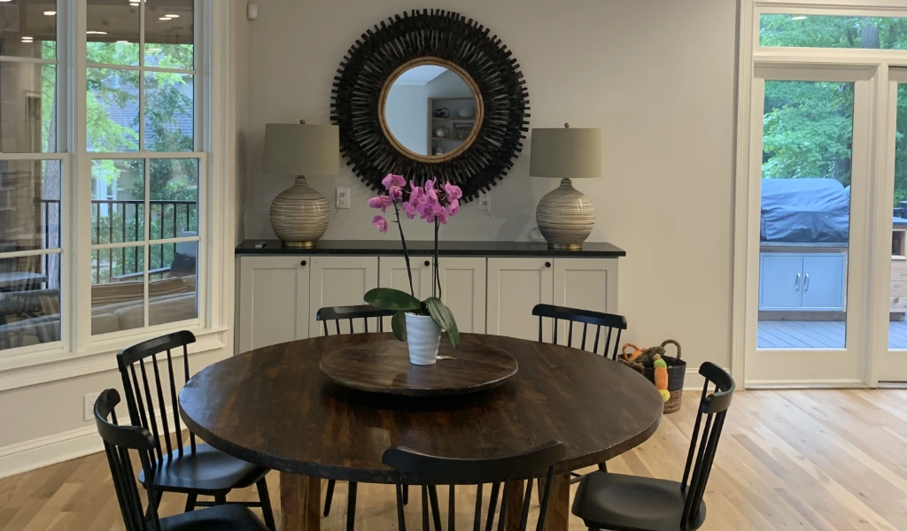 A dining room table with black chairs and a mirror.